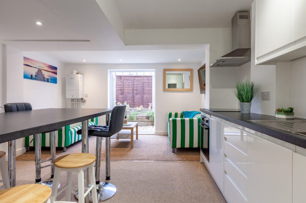 Open-plan kitchen and living area at 24 Granville Street, Cheltenham, with breakfast bar stools and sofas